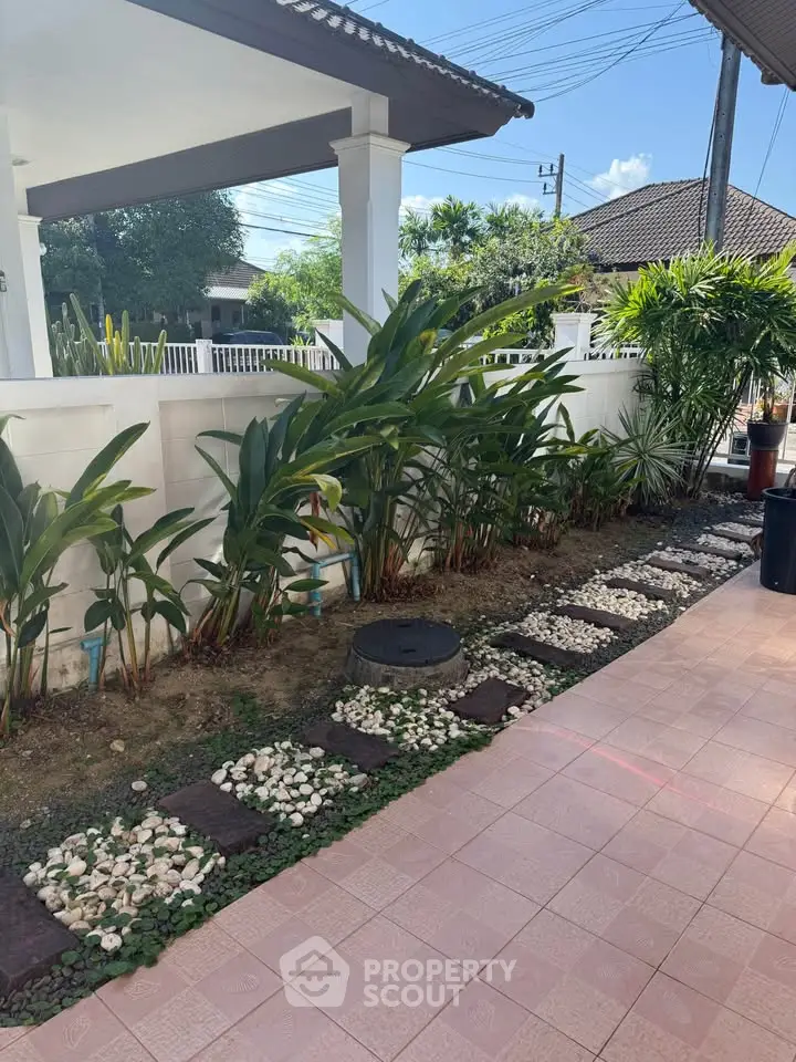 Charming garden view with tiled patio and lush greenery in a serene residential setting.