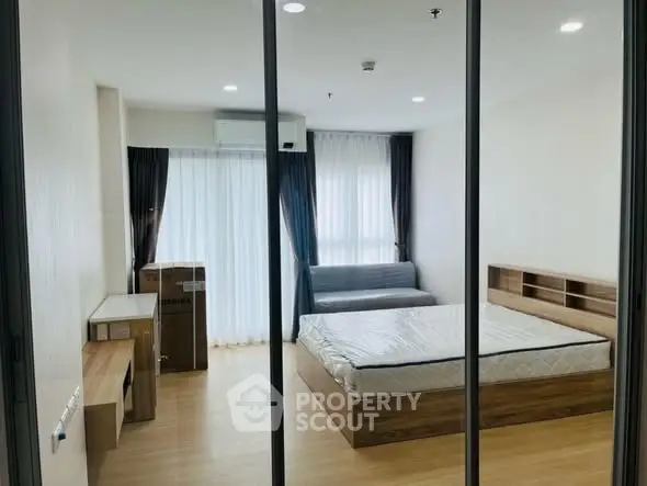 Modern bedroom with large windows and wooden furniture, featuring a cozy bed and ample natural light.