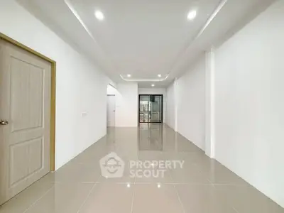 Spacious empty room with glossy tiled flooring and modern lighting, ideal for customization.