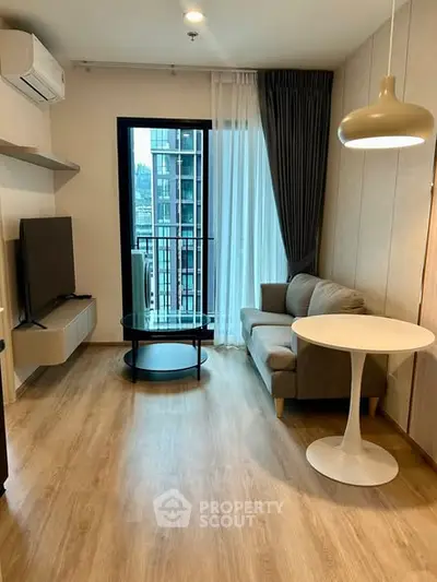 Modern living room with balcony, featuring sleek furniture and a city view.