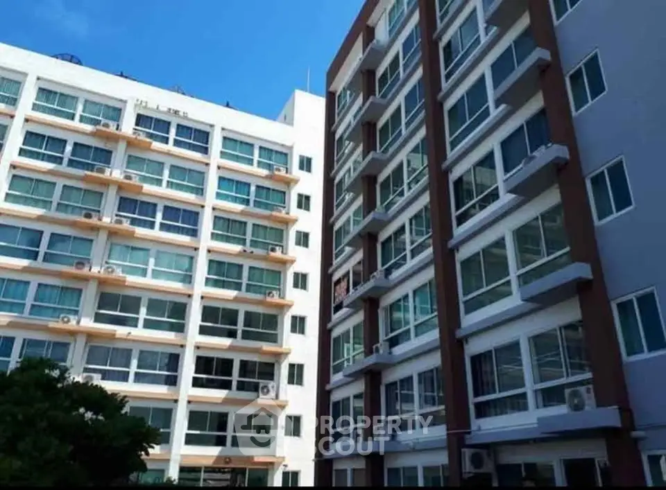 Modern multi-story apartment buildings with large windows and balconies under a clear blue sky.