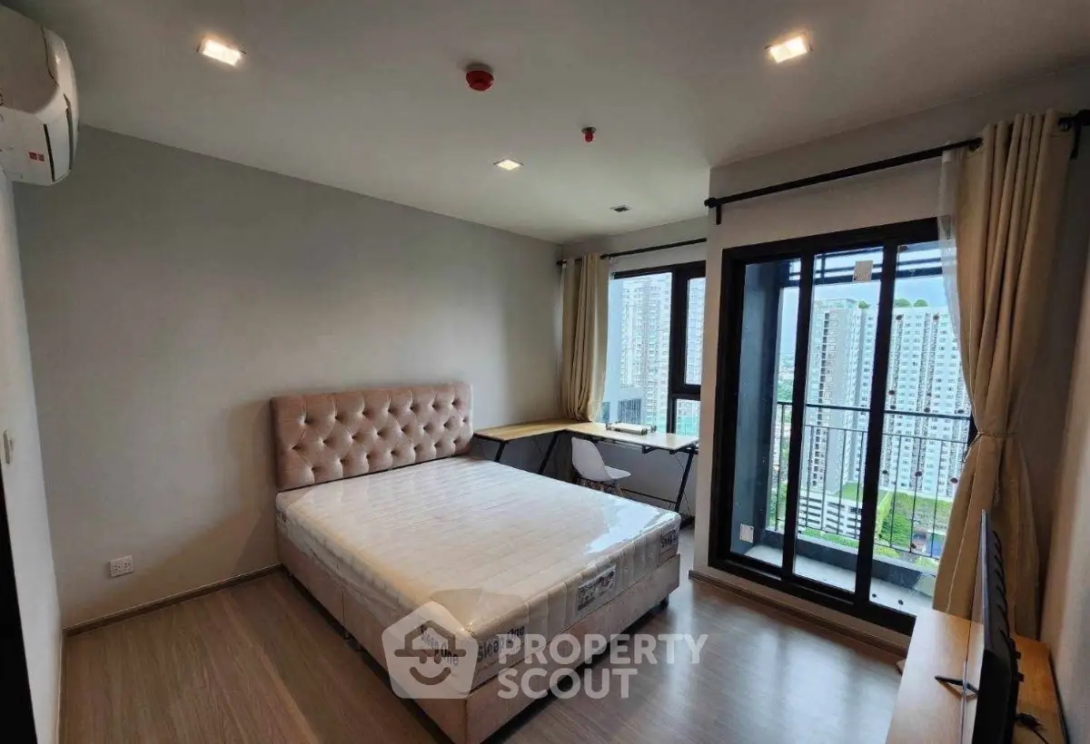 Modern bedroom with city view and balcony access in high-rise apartment
