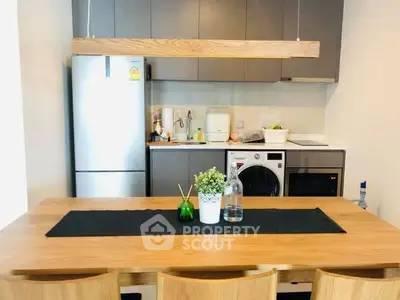 Modern kitchen with wooden dining table, sleek cabinets, and built-in appliances.