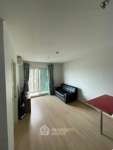 Spacious and well-lit living room with hardwood floors, comfortable seating, and access to a sunlit balcony, ideal for relaxation and entertaining.