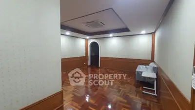 Spacious empty room with elegant wooden flooring and recessed lighting