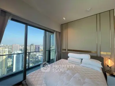 Luxurious bedroom with stunning city view from high-rise balcony.