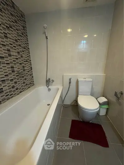 Modern bathroom with sleek tiles and bathtub in contemporary apartment.