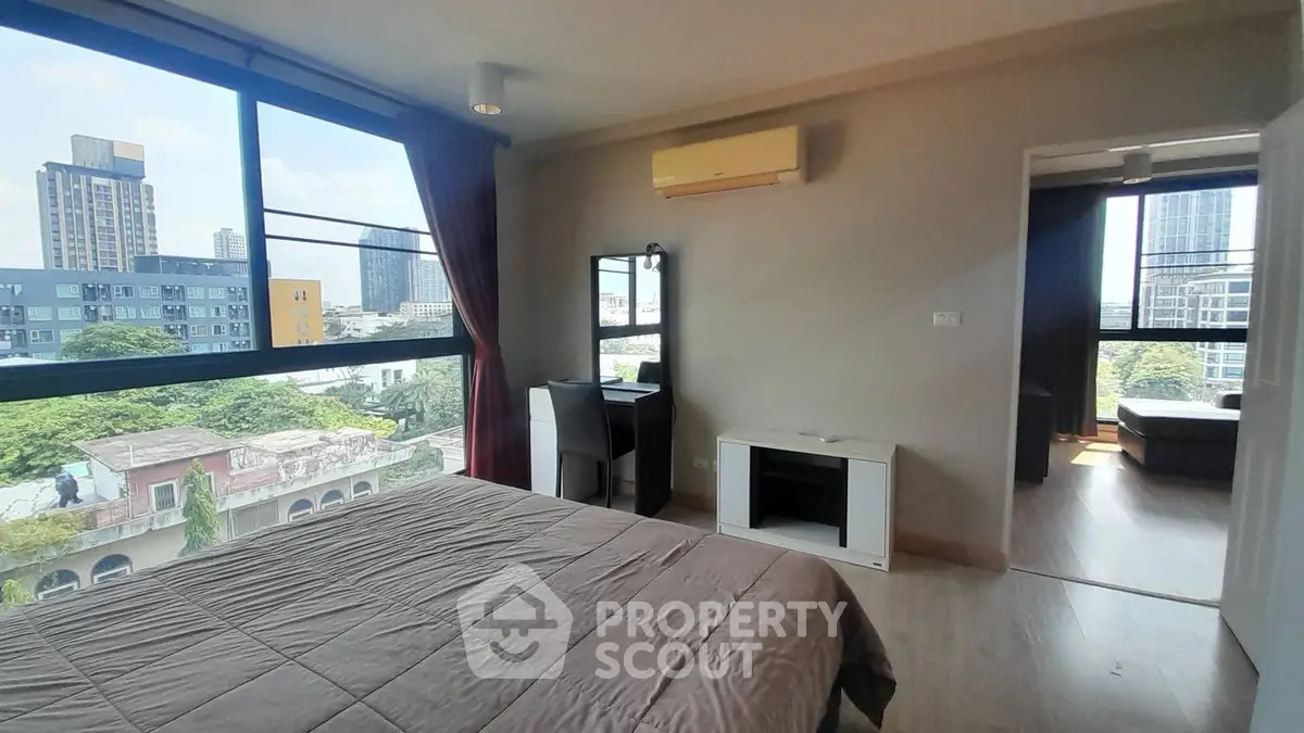 Spacious bedroom with large windows offering city views in modern apartment