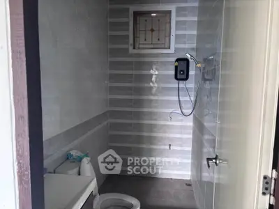 Modern bathroom with sleek tiles and shower heater in a contemporary home.