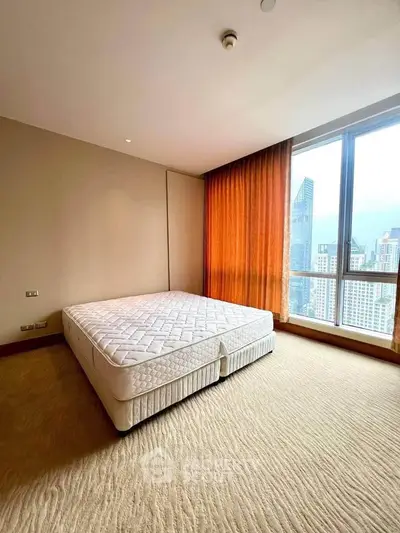 Spacious bedroom with large window offering stunning city views in modern apartment.