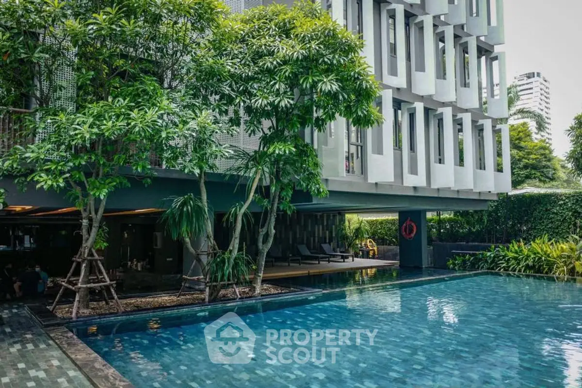 Luxurious modern building with serene pool and lush greenery