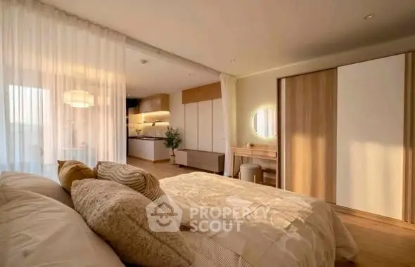 Spacious bedroom with modern decor and open layout leading to a stylish kitchen.