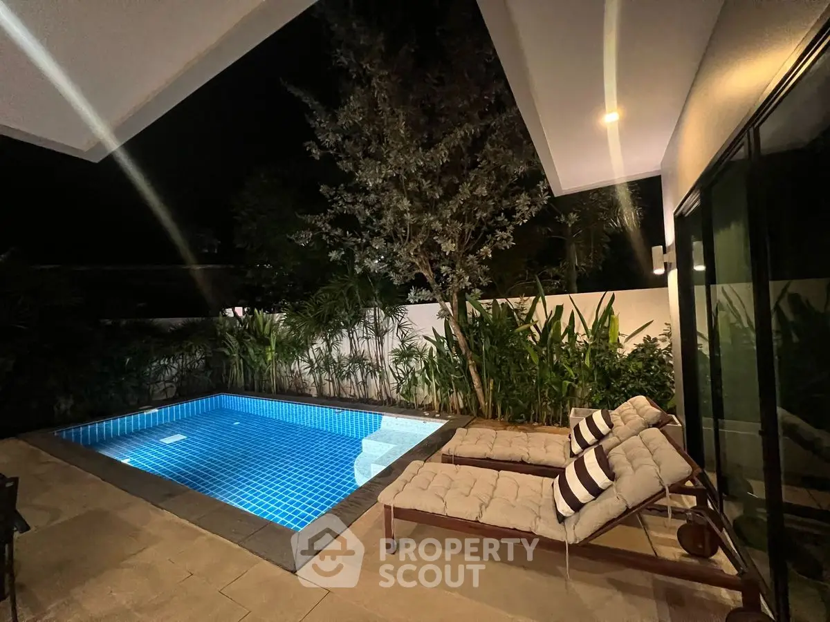 Luxurious night view of private pool with cozy loungers and lush greenery