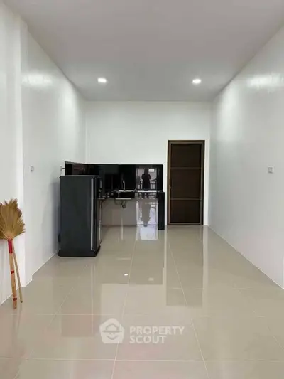 Spacious unfurnished room with glossy tiled floor and modern appliances, ideal for customization.