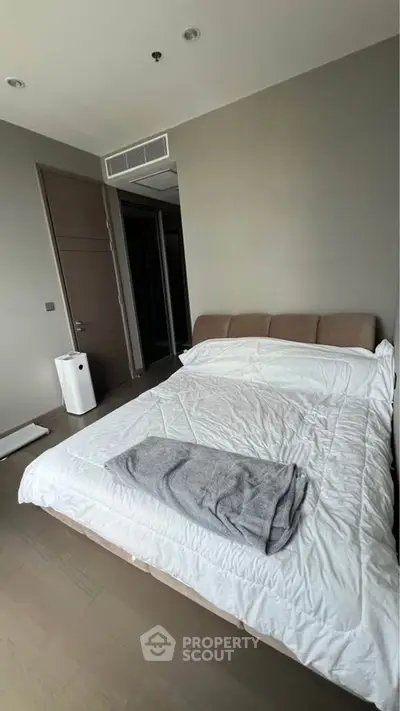 Modern bedroom with cozy bedding and neutral tones, perfect for relaxation.