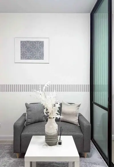 Modern living room with stylish gray sofa, decorative pillows, and elegant vase on a white coffee table.