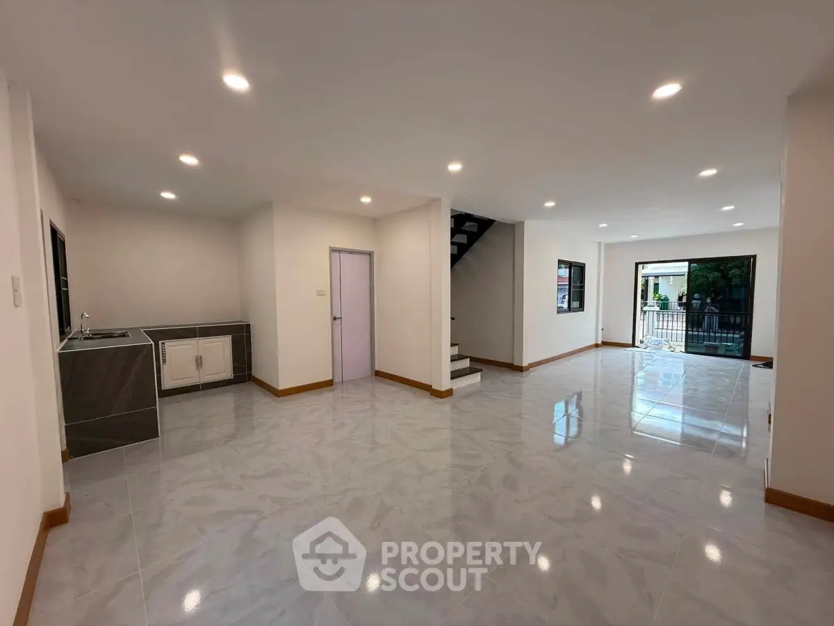Spacious open-plan living area with modern kitchen and staircase, ideal for family gatherings.