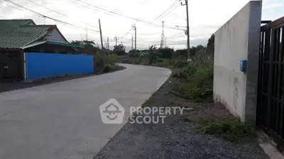 Quiet suburban road with adjacent residential properties and open land, ideal for development.
