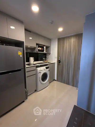 Modern compact kitchen with washing machine and sleek appliances in a stylish apartment.