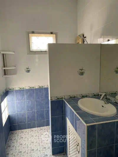 Charming bathroom with blue and white tiles, featuring a modern sink and shower area.
