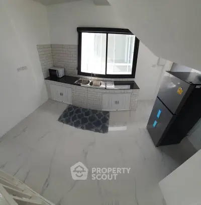 Modern kitchen with sleek black countertop, white cabinets, and large window for natural light.