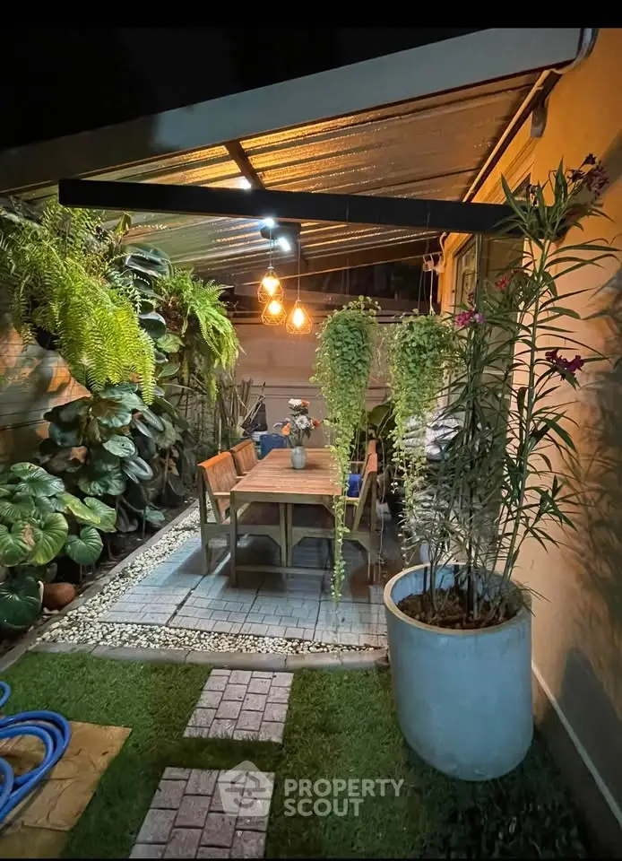 Charming outdoor garden patio with lush greenery and cozy dining area, perfect for entertaining.