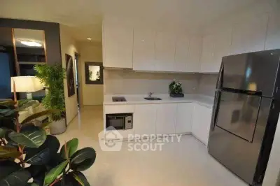 Modern kitchen with sleek white cabinets and stainless steel appliances in a stylish apartment.