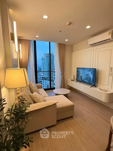 Modern living room with city view, featuring cozy sofa and large TV, perfect for relaxation.