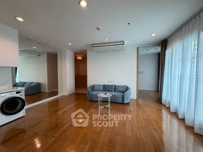 Spacious living room with wooden floors, large windows, and modern furniture in a stylish apartment.