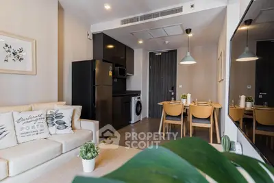 Modern living room with sleek kitchen and dining area, featuring stylish decor and cozy ambiance.