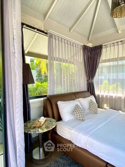 Luxurious bedroom with large windows and elegant decor in a serene setting.