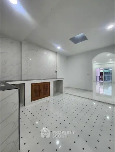 Spacious modern kitchen with elegant marble flooring and ample storage space.
