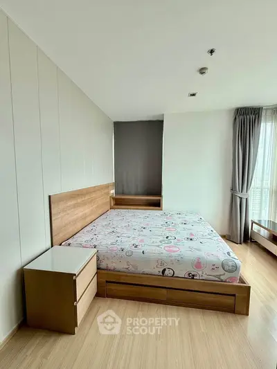 Spacious bedroom with wooden flooring and modern furniture in a bright apartment.