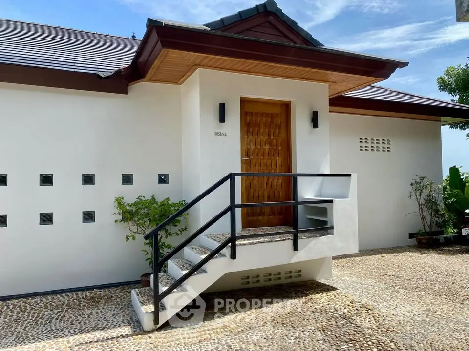Charming modern home entrance with stylish wooden door and pebble stone pathway.