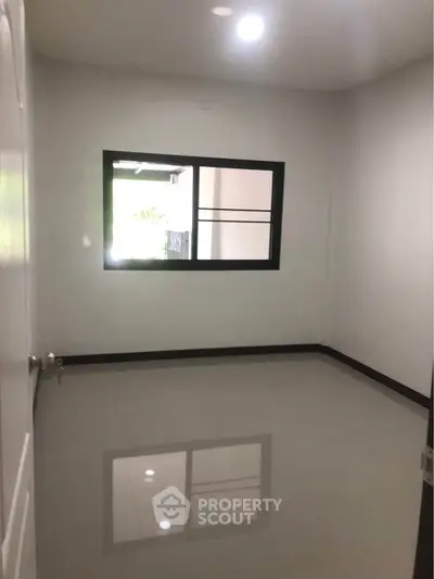 Spacious empty room with glossy tiled floor and window, perfect for customization.