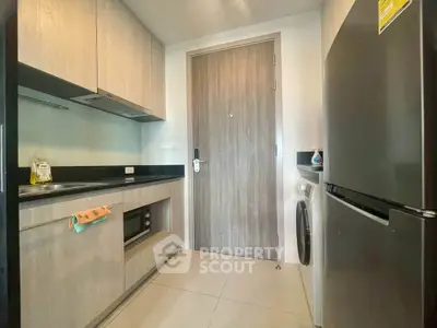 Modern kitchen with sleek cabinetry, built-in oven, and stainless steel fridge in a compact layout.
