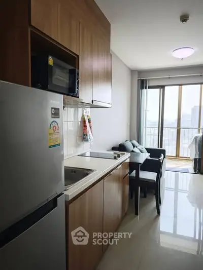 Modern kitchen with sleek cabinetry and dining area in a high-rise apartment with city view.