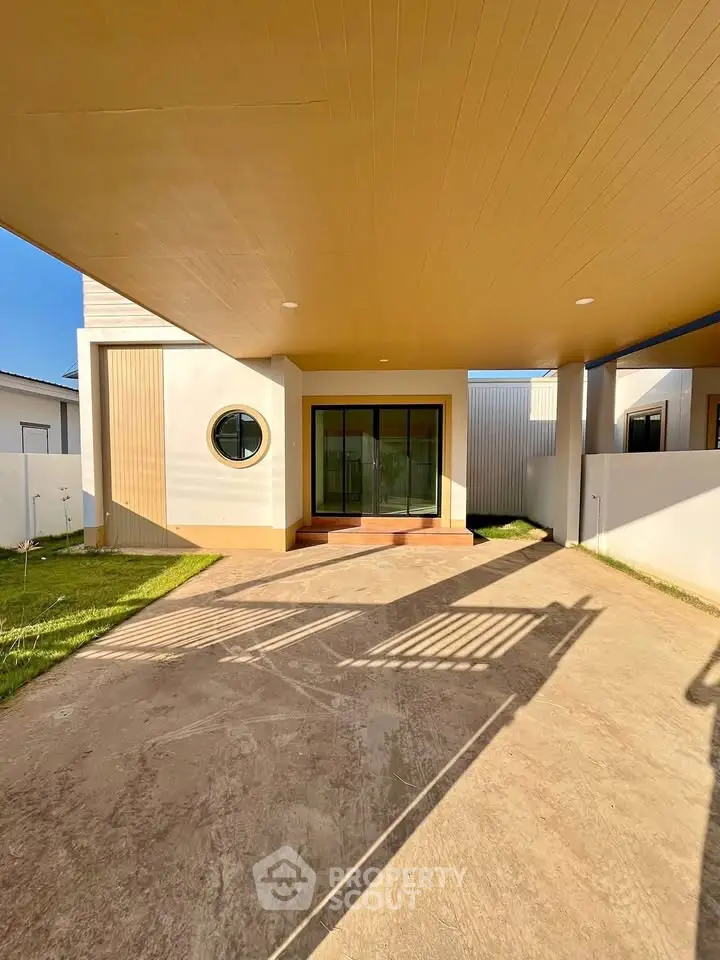 Modern house exterior with covered parking and unique circular window design.