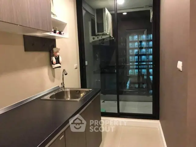 Modern kitchen with sleek cabinetry and glass sliding door to balcony.