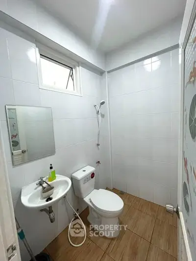 Modern bathroom with sleek white tiles and compact fixtures, ideal for urban living.