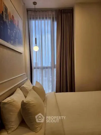 Cozy bedroom with modern decor and large window offering natural light.