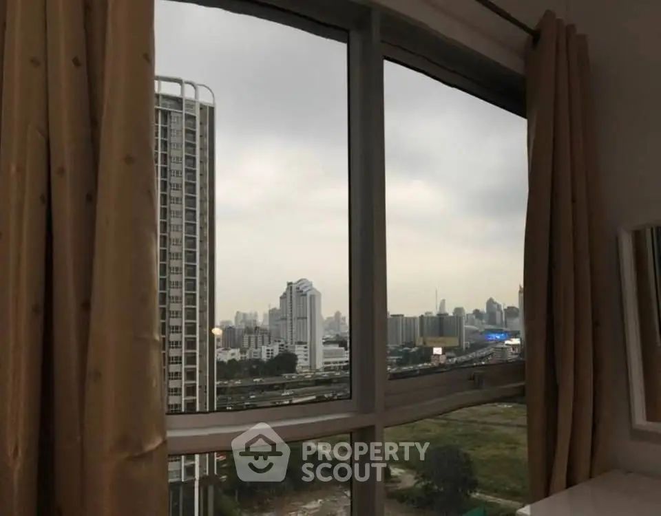 Cityscape view from apartment window with skyline and high-rise buildings.