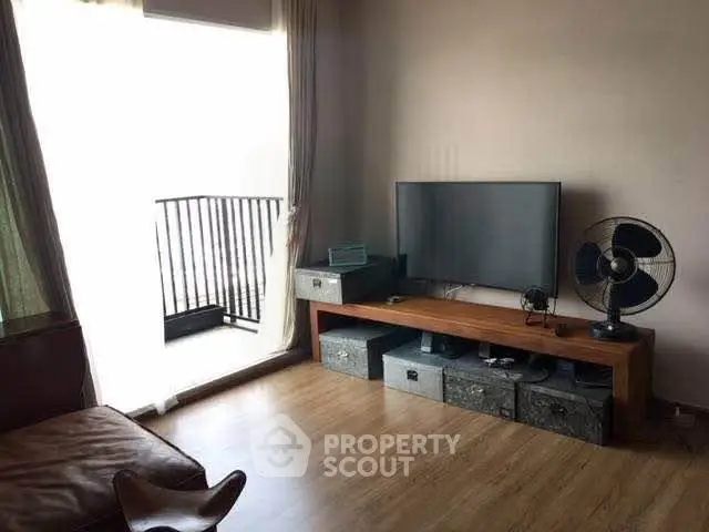Cozy living room with balcony access, featuring modern TV setup and stylish decor.