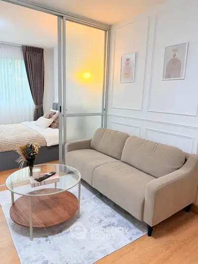 Modern living room with cozy beige sofa and stylish decor adjacent to a serene bedroom.