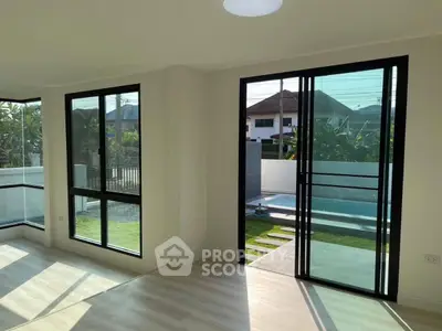 Bright and spacious living area with large windows and garden view, perfect for modern living.