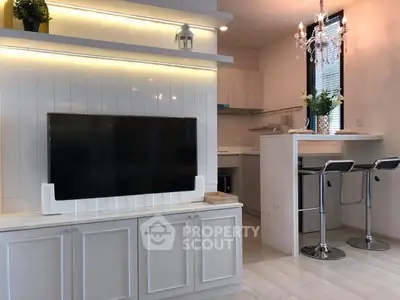 Modern living room with sleek TV setup and stylish kitchen bar area.