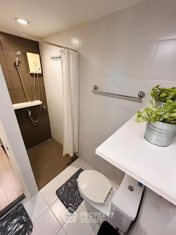 Modern bathroom with shower and white fixtures in a compact layout.