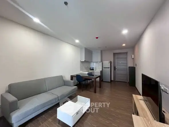 Modern living room with sleek furniture and open kitchen layout.