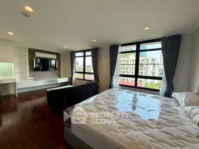 Spacious bedroom with large windows offering city views and modern furnishings.