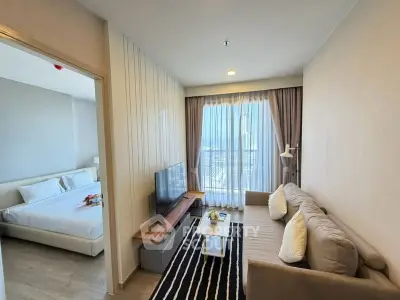 Modern apartment living room with cozy sofa and TV, adjacent to a stylish bedroom.